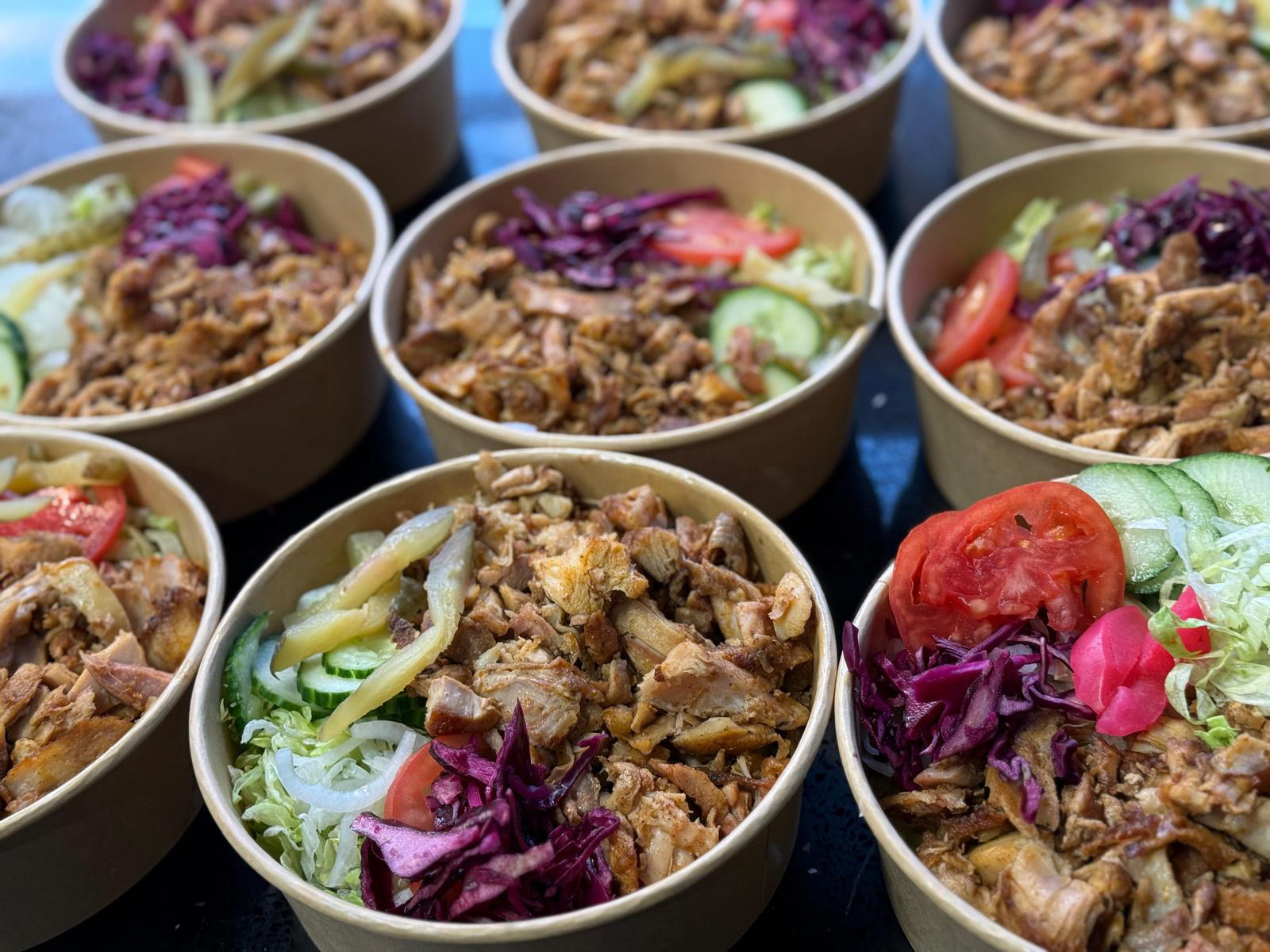 Individually packaged chicken shawarma bowls with lettuce, cucumber, tomato, pickles and red cabbage
